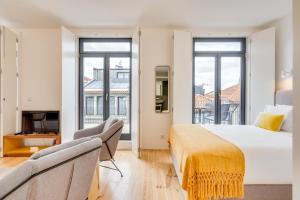 Un dormitorio con una cama y un sofá y ventanas. en Alma da Casa by DA'HOME, en Oporto