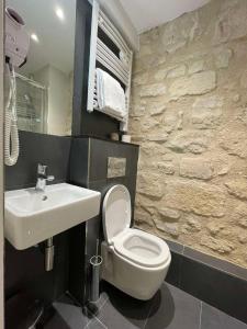 La salle de bains est pourvue de toilettes blanches et d'un lavabo. dans l'établissement Hôtel De La Herse d'Or, à Paris