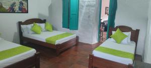 2 letti con cuscini verdi in una stanza di HOSPEDAJE CASA GRANDE ARBOLITO a Barichara
