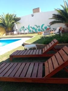 una piscina con 2 bancos de madera frente a un edificio en Hotel Buenavista - BV Hoteles en La Falda