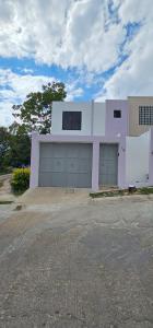 una casa blanca con dos puertas de garaje en un estacionamiento en casa violeta norte, en Tuxtla Gutiérrez