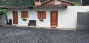 uma pequena casa branca com portas e cadeiras castanhas em Refugio Victoria em Monte Verde