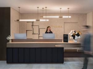 a woman standing at a reception desk in an office at The Sebel Sydney Martin Place in Sydney