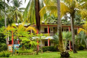 a building with palm trees in front of it at Playa Mareygua Hostal in Buritaca
