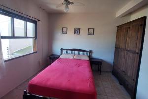 ein Schlafzimmer mit einem roten Bett und einem Fenster in der Unterkunft Casa de praia in Itapoa
