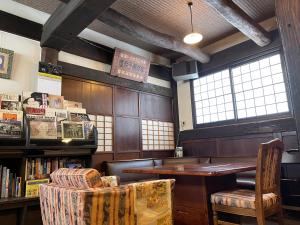 a room with a table and chairs and a book shelf at Rickshaw inn in Takayama