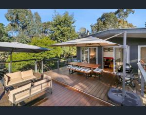 a deck with benches and umbrellas on a house at Wanyiora - Lake views and family friendly in Jamieson