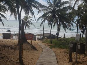 a wooden path on a beach with palm trees at Estrela Antônia - Praia de Santo Antônio in Matta de São João