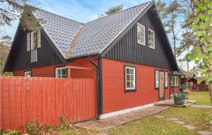 une maison rouge avec un toit noir et une clôture rouge dans l'établissement Lovely Home In Hllviken With Kitchen, à Höllviken