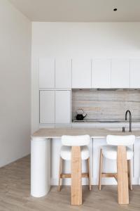 a kitchen with white cabinets and white bar stools at Luxury 4BR Ocean View Villa Near Bingin Beach in Uluwatu