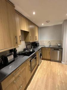 a kitchen with wooden cabinets and stainless steel appliances at Contemporary, Stylish Apartment in Weston in Worle