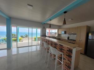 cocina con barra con sillas y vistas al océano en 321 Surprise Beach house and Glamping, en Providencia