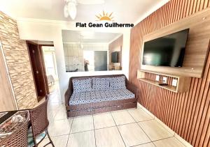 uma sala de estar com um sofá e uma televisão de ecrã plano em Flat Gean Guilherme - Canasvieiras em Florianópolis