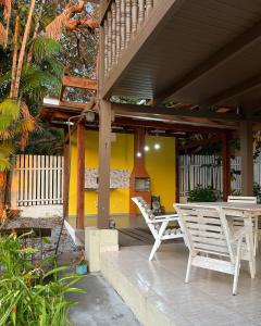 a porch with two white chairs and a table at Chalé Rute Bilby Alter Do Chão in Santarém