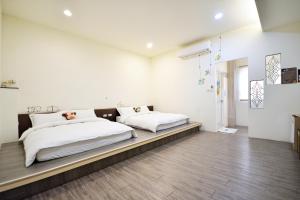 2 camas en un dormitorio con paredes blancas y suelo de madera en Jamie home stay, en Taitung