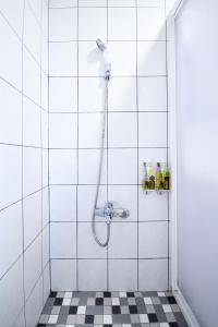 a shower with a hose in a white tiled bathroom at Jamie home stay in Taitung City