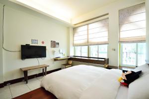 1 dormitorio con 1 cama y TV de pantalla plana en Jamie home stay, en Taitung