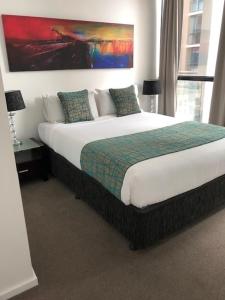 ein Schlafzimmer mit einem großen Bett und einem Gemälde an der Wand in der Unterkunft RNR on Franklin in Adelaide