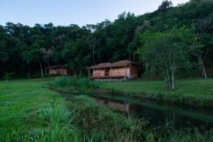 a house in a field next to a river at pousada do caneca in Senador Amaral