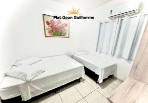 um quarto branco com 2 camas e uma janela em Flat Gean Guilherme - Canasvieiras em Florianópolis