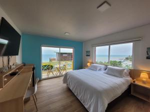 1 dormitorio con 1 cama y escritorio con 2 ventanas en 321 Surprise Beach house and Glamping, en Providencia