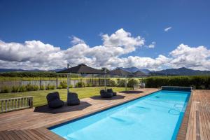 einen Pool mit Liegestühlen neben einer Holzterrasse in der Unterkunft The Cellar Door - Blenheim Holiday Home in Blenheim