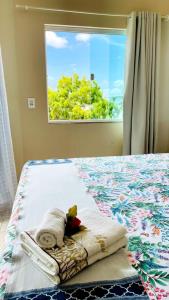 ein Schlafzimmer mit einem Bett mit Handtüchern und einem Fenster in der Unterkunft Pousada OPA - O Paraíso é Aqui Abrolhos in Caravelas