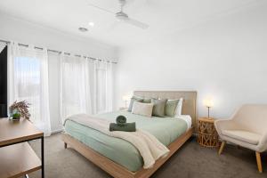 a bedroom with a large bed and a chair at Salty Sage Beach House in Torquay