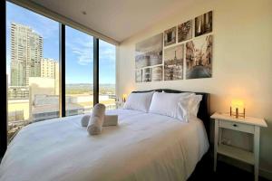 a bedroom with a white bed with a large window at City Chic Living: 1-BR APT Overlooking Rundle Mall in Adelaide