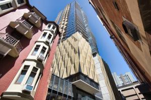 un rascacielos alto en medio de dos edificios en City Chic Living: 1-BR APT Overlooking Rundle Mall en Adelaida