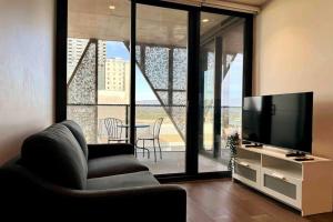 uma sala de estar com uma televisão, uma cadeira e uma mesa em City Chic Living: 1-BR APT Overlooking Rundle Mall em Adelaide