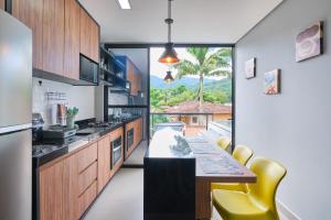 a kitchen with a dining table and yellow chairs at Villa da Serra 2 - Casa com piscinas privativas vidro in Paraty