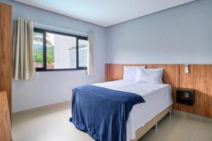 a bedroom with a bed with a blue blanket on it at Villa da Serra 2 - Casa com piscinas privativas vidro in Paraty +76 photos