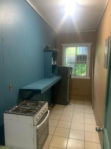 uma cozinha com um fogão e uma parede azul em No Regrets em Coxen Hole