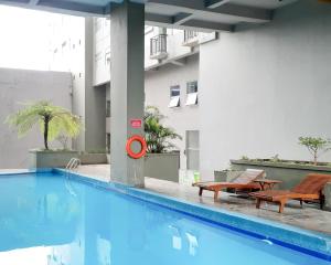 a swimming pool with two tables and chairs next to a building at Beriruang in Bandung