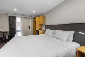een slaapkamer met een groot wit bed en een bureau bij Apollo Bay Motel & Apartments, BW Signature Collection in Apollo Bay