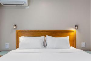 Apollo Bay Motel & Apartments, BW Signature Collection في خليج أبولو: سرير مع وسائد بيضاء و اللوح الأمامي الخشبي