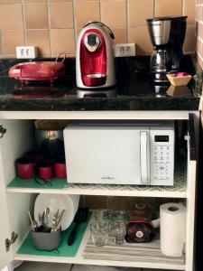 a kitchen shelf with a microwave and other kitchen items at Gran Lençóis Flat Barreirinhas APT 510 in Barreirinhas