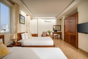 a hotel room with two beds and a television at Titan Hotel Da Nang in Da Nang