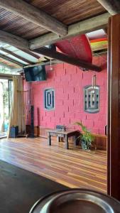 Habitación con una pared de ladrillo rosa y una mesa. en Recanto da Vó Dilma sossego do campo perto do mar, en Imbituba