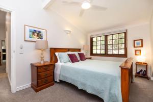 a bedroom with a large bed and a window at Grande Eden - Private Cotswold Cottage in Bilambil