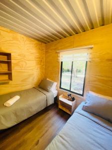 1 dormitorio con 2 camas y ventana. en Pucura Eco Lodge, en Licán Ray