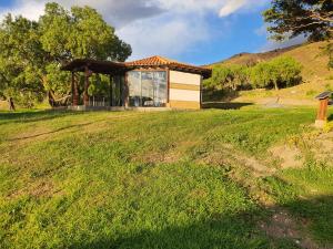 a building in a field with a grassy field at Cabañas Villa Celeste in Villa de Leyva