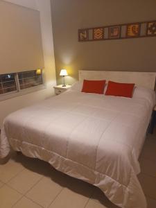 1 dormitorio con 1 cama blanca grande con almohadas rojas en Duplex tipo Casa Mendoza en Villa Hipódromo