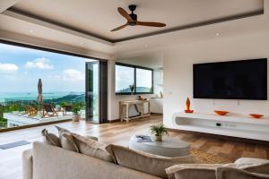 a living room with a ceiling fan and large windows at Luxury 5 bedroom oceanview villa in Bophut with Staff in Amphoe Koh Samui