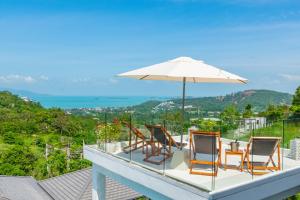 a balcony with a table and chairs and an umbrella at Luxury 5 bedroom oceanview villa in Bophut with Staff in Amphoe Koh Samui