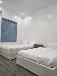 two beds in a white room with a window at Milano Hotel in Hải Dương