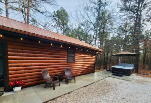 a log cabin with two chairs and a grill at Coppermoon Cabin in Broken Bow