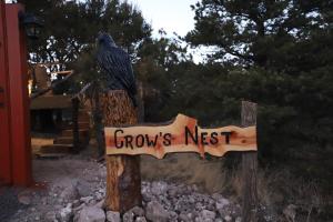 um pássaro sentado num cartaz que lê o ninho das setas em Crows Nest Treehouse At El Mstico Ranch em Nogal