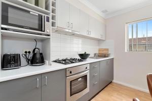 uma cozinha com um micro-ondas e um fogão forno superior em 8 Cute Cunningham Close To Subiaco - Sleeps 4 em Perth